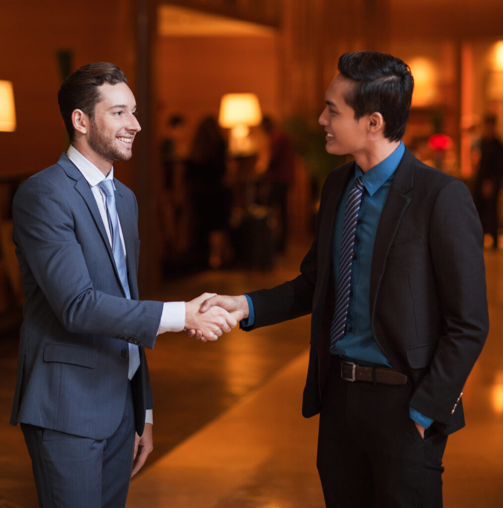 two smiling partners shaking hands in lounge